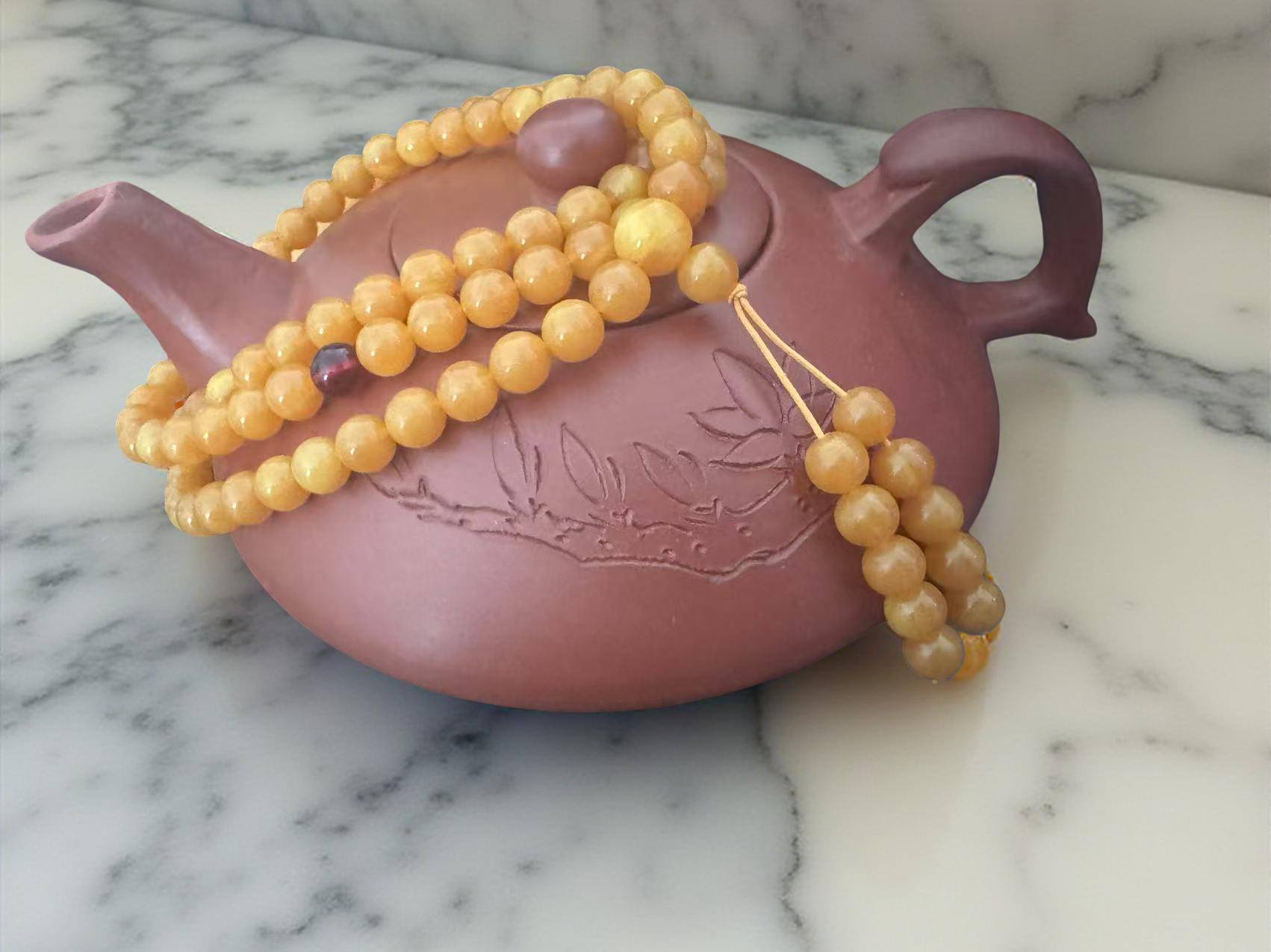 Mala aus Kunst-Bernstein auf einer Teekanne, ideal für Meditation und Yoga, klassischer tibetischer Stil.